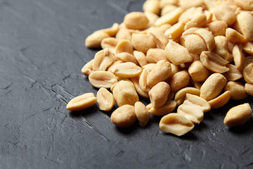Peanuts closeup. Heap of roasted peeled peanuts, salty beer snack on black table