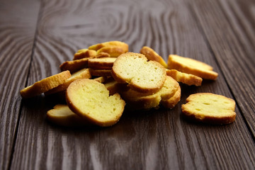 Bruschette chips, slices of baked bread, heap of dry snacks on wooden background