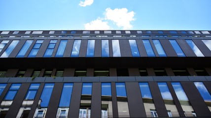 Modern office building windows with vertical lines and reflection. Building reflecting the sky with clouds and creating a surreal view.