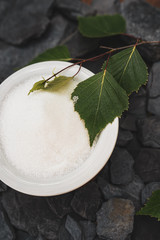 Birch sugar, also known as xylitol is a natural vegetable sweetener. in the photo a bowl of xylitol and birch leaves