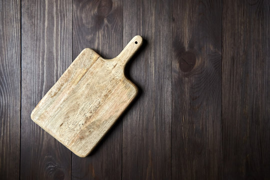Cutting board on wooden table with copy space, top view. Empty pine chopping board
