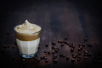 trendiger Dalgona Kaffee im Glas auf Holz mit Kaffeebohnen. Platz für Text, Querformat und geringe...