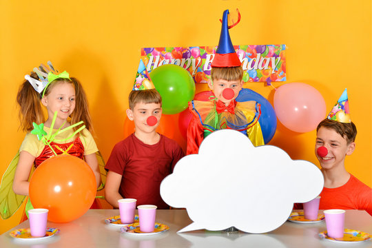 Four festively dressed children are looking at an empty cloud.