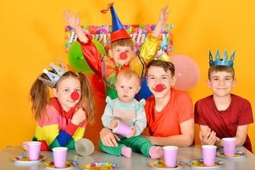 Five children celebrate a birthday at the table with a clown.