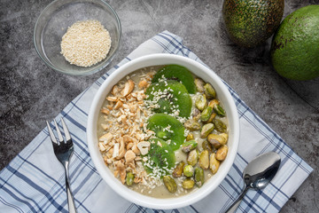 Avocado Smoothie Breakfast bowl (avocado , banana , almond milk, Natural flavored yogurt) topped with Dry Kiwi Slice Welding, Pistachio, chopped  nuts and sesame seeds. Top View. Vegan Food