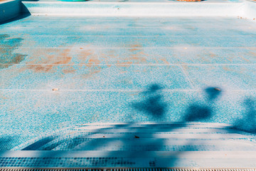 Blue old pool, dry and dirty at the bottom. Copy space. View from steps. Concept of maintenance and...