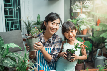 cheerful mother and daugther while planting in the garden at home