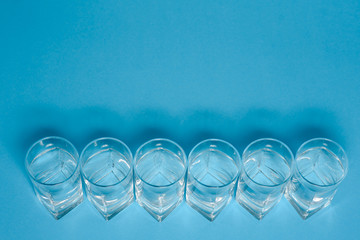 Line of glasses, a glass with water, on a light blue background. Difference concept. Equality concept.