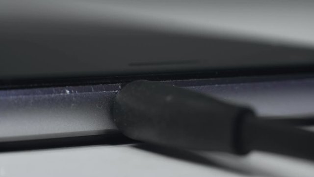 Macro, fingers connect audio TRRS 3.5 mm mini-jack headset to smartphone connector to listen music. Cable standard for headphones. Audiophile. Social networks addiction.