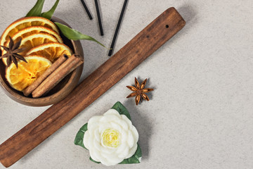 Incense sticks with stand, sliced in orange circles in a wooden bowl and anise star, cinnamon sticks on a gray background.Candle in the form of a flower and a shell.Aromatherapy. Home spa concept.