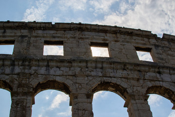 Wall of the Pula Arena, the only remaining Roman amphitheatre entirely preserved, with clouds on the sky at the background, in Pula, Croatia