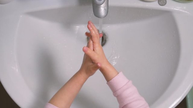 Top view of kid washing her hands with soap