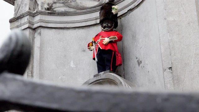 Manneken pis fountain statue in Brussels Belgium dressed up as a British soldier in bearskin hat, Pedestal up reveal shot