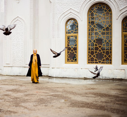Young muslim woman walks near the beautiful mosque and smiles