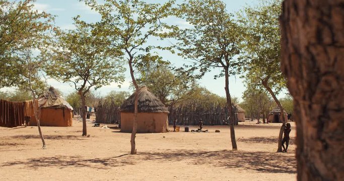 Footage of a village of Hamba people with authentic huts and people walking, 4k