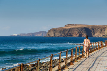 Young woman walks alongside the Atlantic Ocean, the coast of Gran Canaria