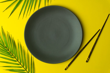 Empty plate on a yellow background. Empty plate for asian and chinese food and cuisine with chinese chopsticks