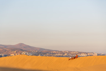 Fototapeta na wymiar Maspalomas ,people sitting at the beach of Maspalomas Gran Canaria Spain, at the sand dunes desert of Maspalomas