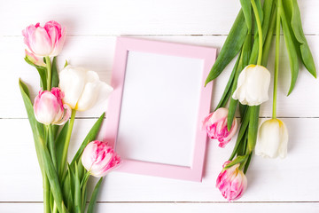 Beautiful white and pink tulips and photo frame for your text on white wooden background.