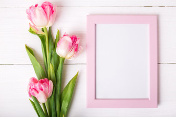 Beautiful white and pink tulips and photo frame for your text on white wooden background.