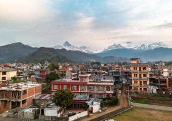 Fototapeta na wymiar A view of the snow capped Annapurna range over the rooftops of the concrete houses of the city of Pokhara in Nepal.