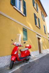 Typical street scene in Rome. Red old scooter near traditional yellow  house