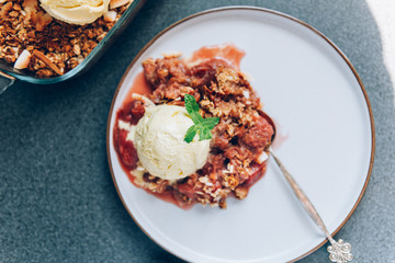 Home cooked Rhubarb and Strawberry crumble from oatmeal and nuts topping and with vanilla ice cream scoops