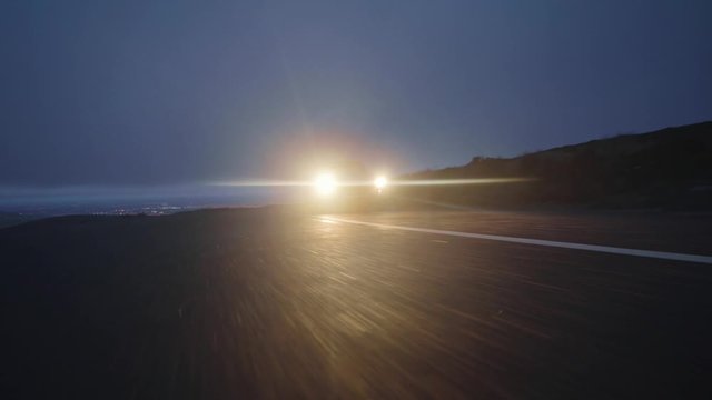 Low angle shot of high speed vintage car driving towards camera at blue hour sun rise. Anamorphic lens flare. Cinematic 4k in the snow.