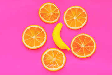 Obraz na płótnie Canvas Yellow banana and oranges on pink paper. Fruits modern image. Flat lay. Top view. Pop art style. Creative minimalism.