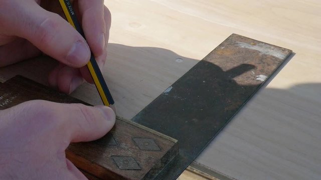 Carpenter Measures Wood Plank With Angle Ruler Or L Square And Tape Measures And Marks Interfaces Using A Pencil. - close up shot