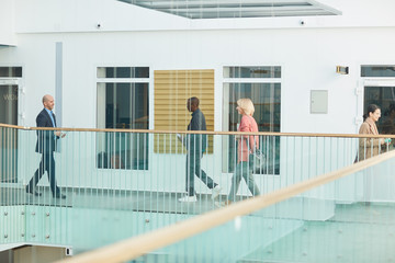 Businessmen and businesswomen walking along the corridor of office building