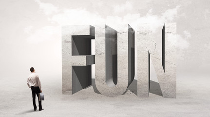 Obraz premium Rear view of a businessman standing in front of FUN abbreviation, attention making concept
