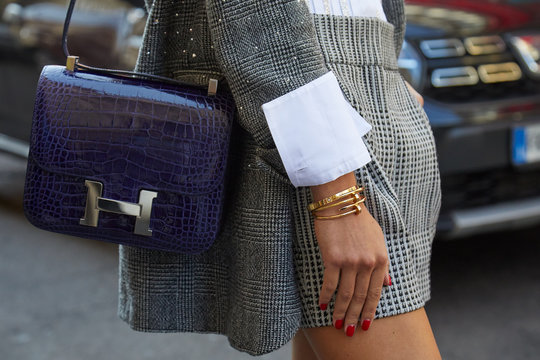 Woman with Hermes crocodile blue leather bag and golden Cartier bracelets on September 21, 2019 in Milan, Italy
