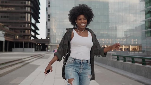 happy young attractive girl smiling listens to music on the phone jumps and dances with happiness
