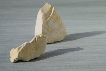 Shattered white clay on the cyan background. Close up. Ural food clay. No people..There is noise...