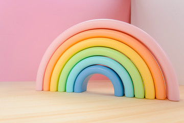 Abstract figures from elements of the children's designer wooden pastel rainbow on a wooden podium.