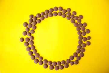 Drops of milk chocolate are placed in a circle on a yellow background