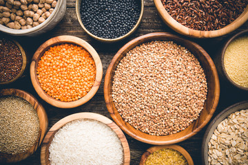 Organic products. Bowls with different gluten free grains on wooden background, top view