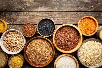 Organic products. Bowls with different gluten free grains on wooden background, top view