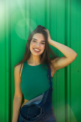 Trendy young woman standing by the green wall