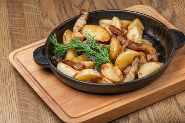 fried potatoes in a pan with slices of bacon