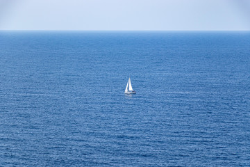 Fototapeta premium beautiful sailboat sailing in the distance in blue Mediterranean sea ocean, mallorca, spain