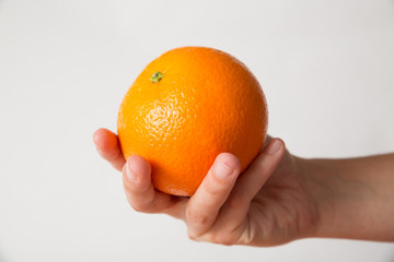 Person offering orange, holding fruit in hand. Cropped shot, side view, isolated on white. Healthy nutrition or organic food concept