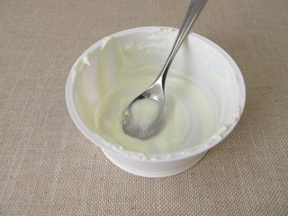 Empty plastic mug with remains of yogurt and a spoon