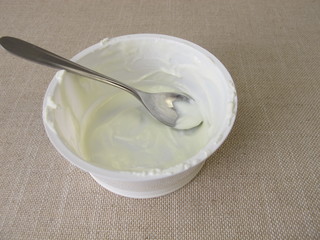 Empty plastic mug with remains of yogurt and a spoon