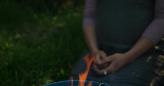 Young woman by a bucket barbecue with flames