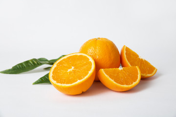 Cut orange slices and half, whole fruit and green leaf isolated on white background. Closeup shot. Natural vitamin or organic food concept