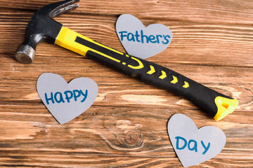 high angle view of hammer and paper cut grey hearts with words happy fathers day on wooden background
