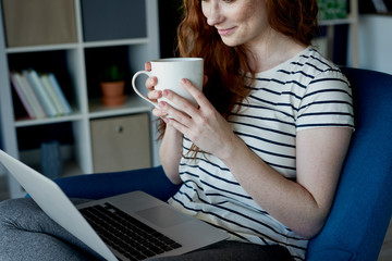 Woman drinking coffee and using her computer