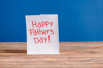 White paper greeting card with red lettering happy fathers day isolated on blue
